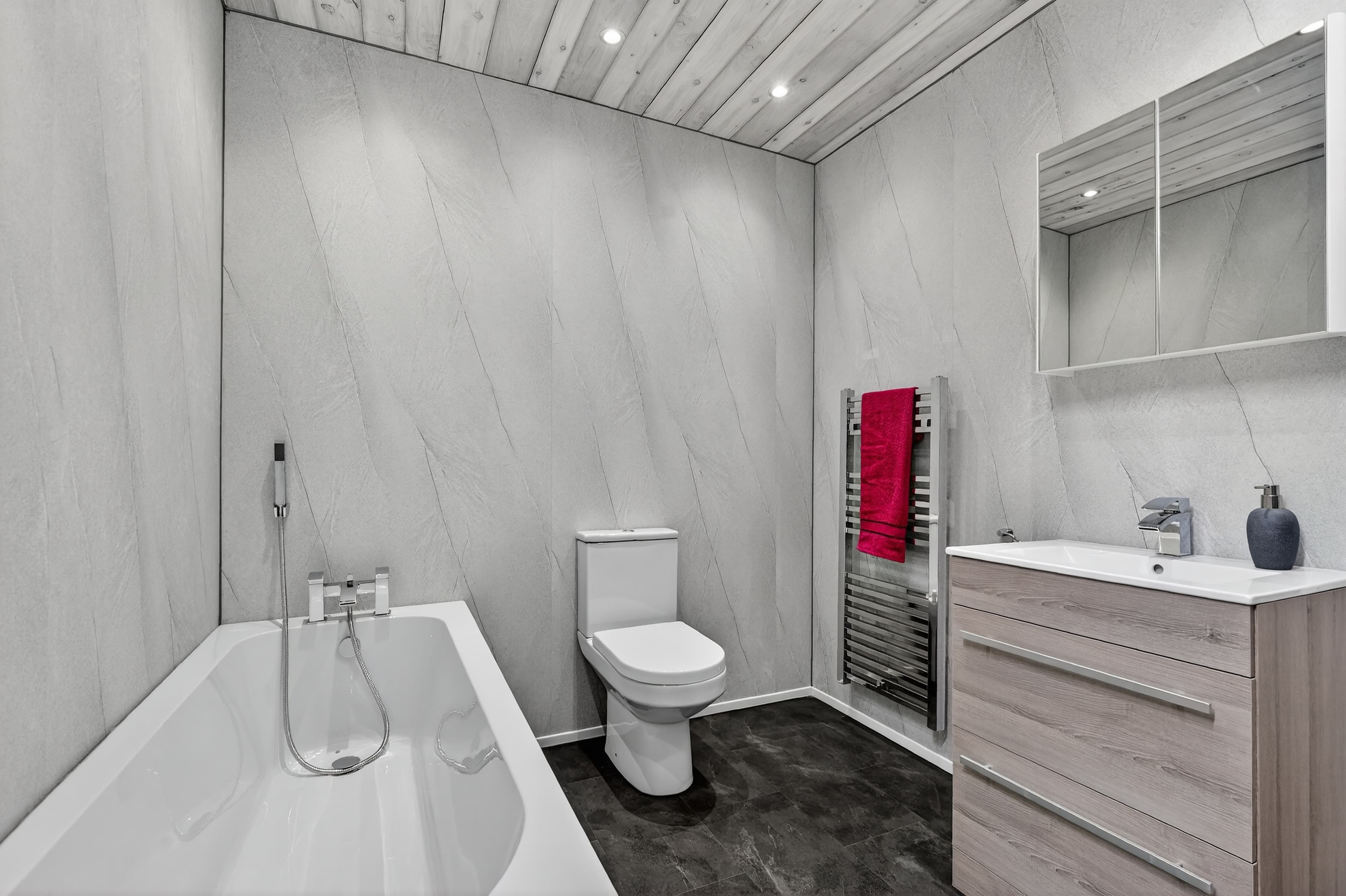 Grey marble-effect PVC wall and ceiling panels with bath, toilet, oak vanity unit and chrome heated towel rail - bathroom trade supplies Belfast M1 Bathrooms